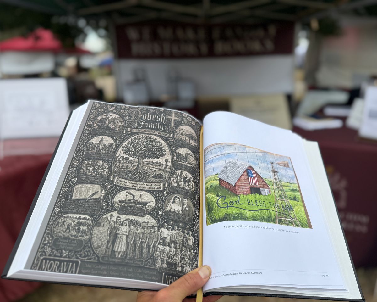 Daniel holding the finished Dobesh family book open to a painting of the family barn